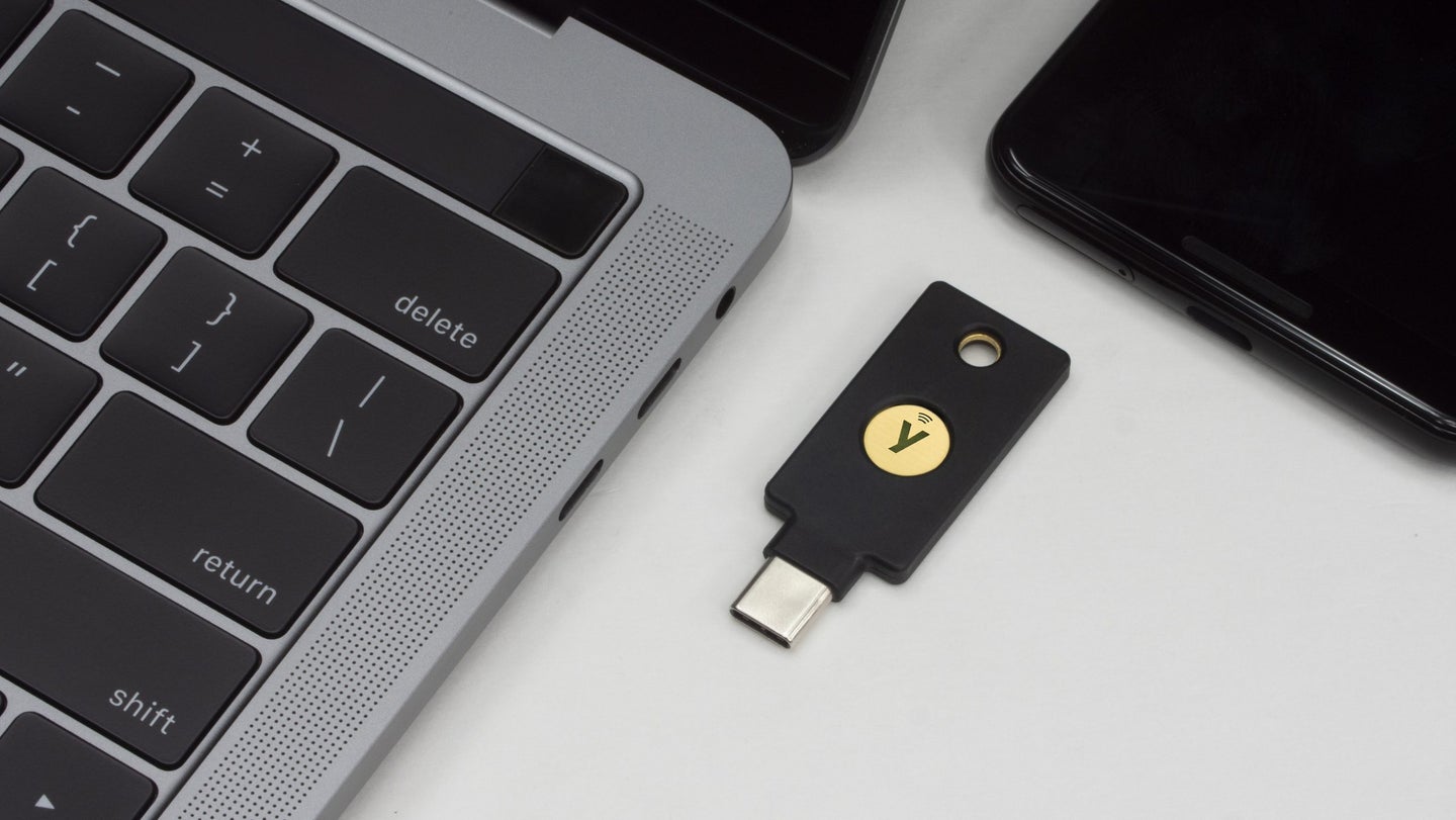 Yubikey security key next to a phone and a MacBook