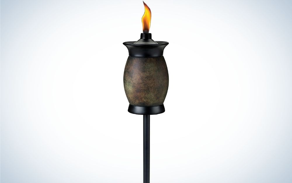 A black torch with a thin metal body and its head like a stone jar with a fire up.