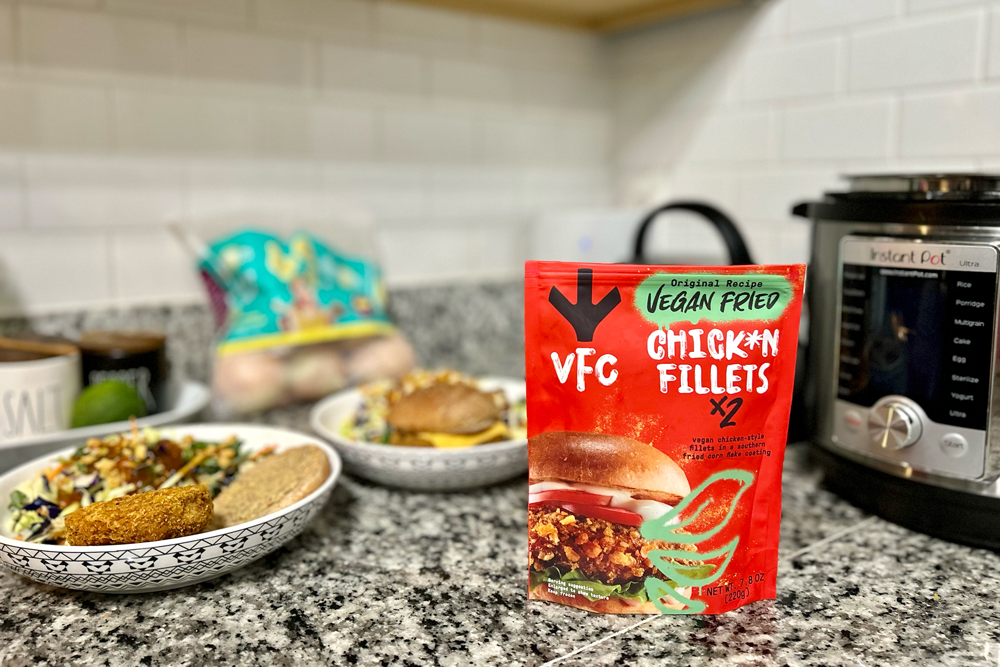 VFC vegan chickn fillet package on the counter between sandwiches and an air fryer