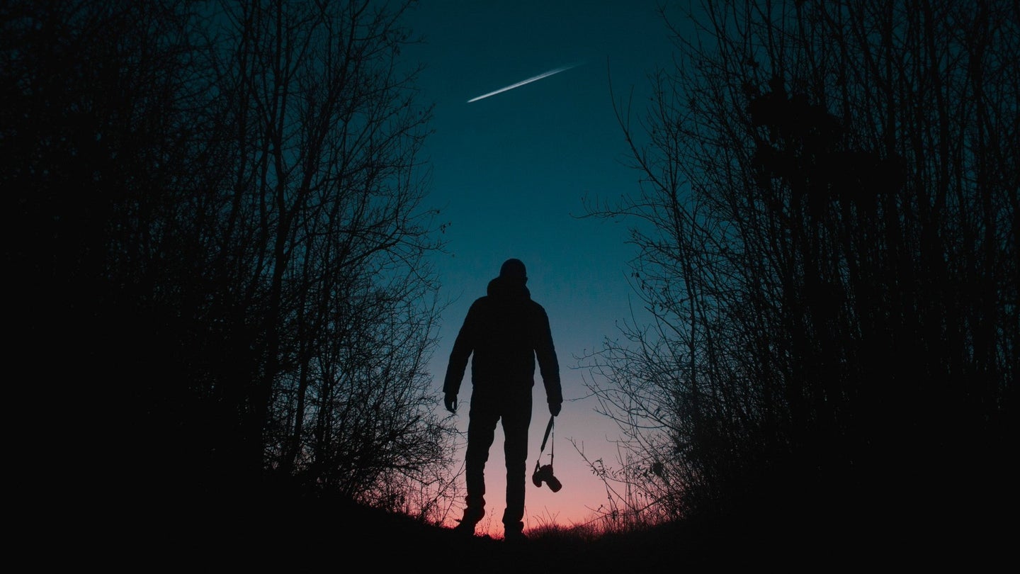 A man walks beneath a shooting star.
