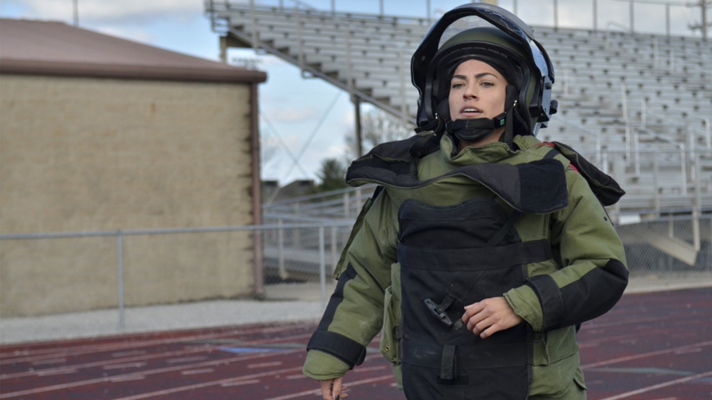 US Army soldier running on a track in a bomb suit