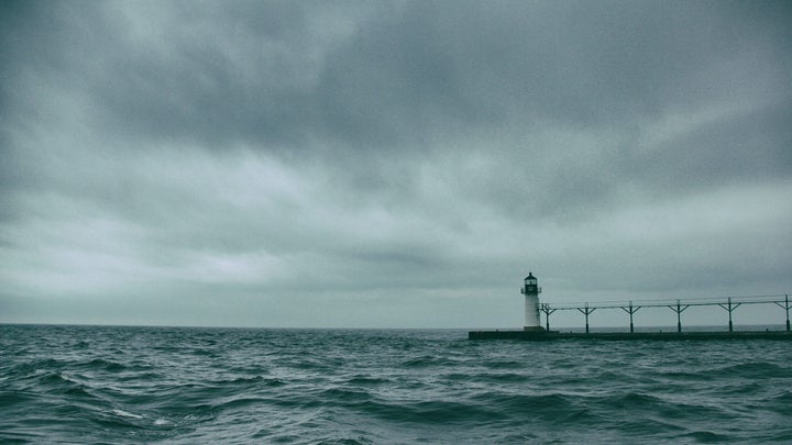 A brewing storm with dark clouds and a lighthouse in Michigan.