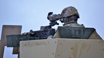 A soldier looks at a gun sight.