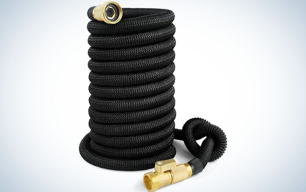 A black garden hose wrapped in a cylindrical shape and with two pieces of gold at its ends.