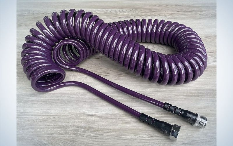 A dark purple coil garden hose set on a gray parquet.