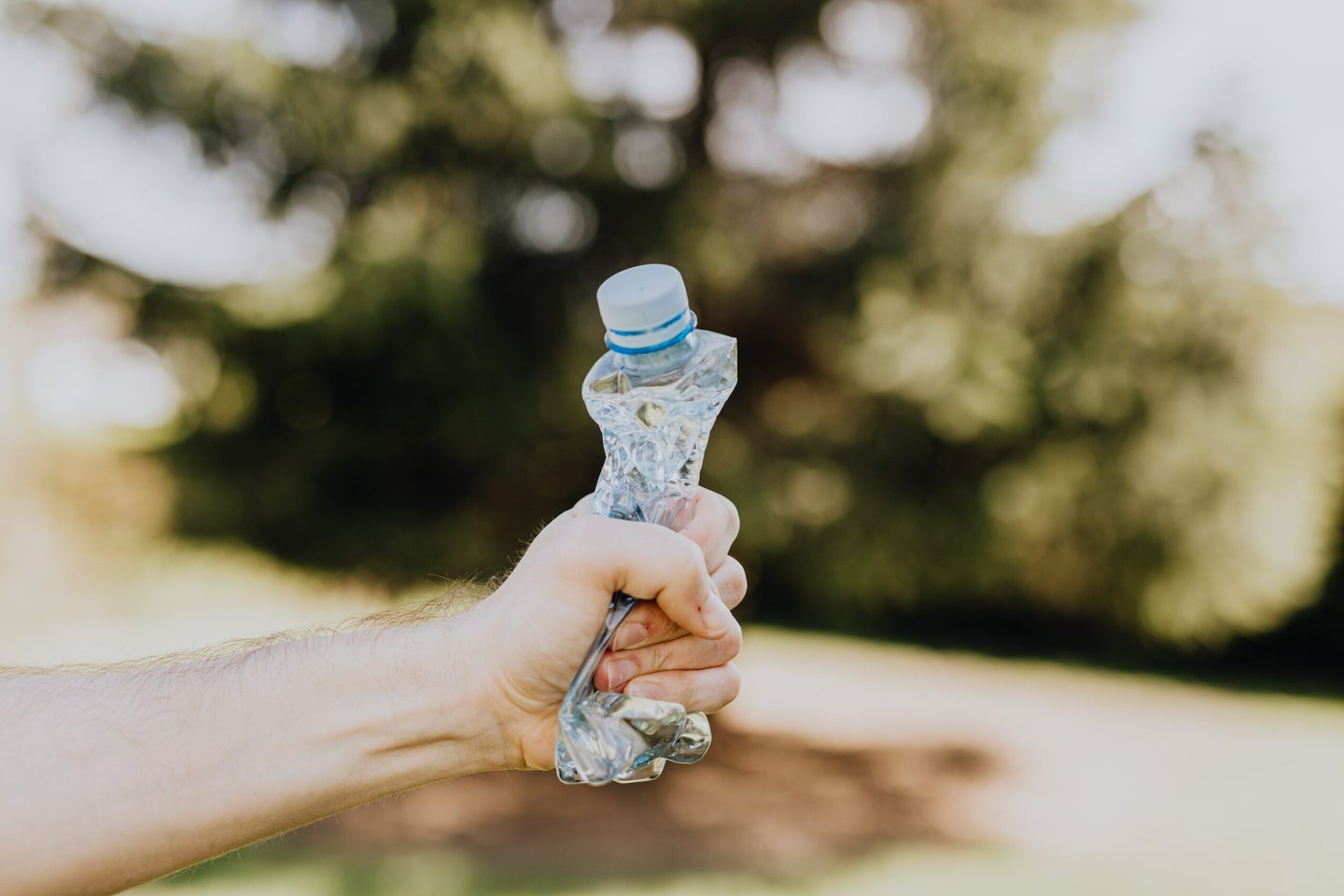 Crushed single-use plastic water bottle in hand.