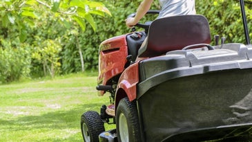 A man riding a lawn mower on the grassy field.