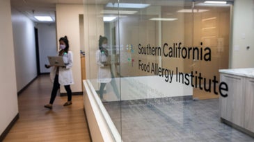 Glass entrance of Southern California Food Allergy Institute with doctor in scrubs walking out