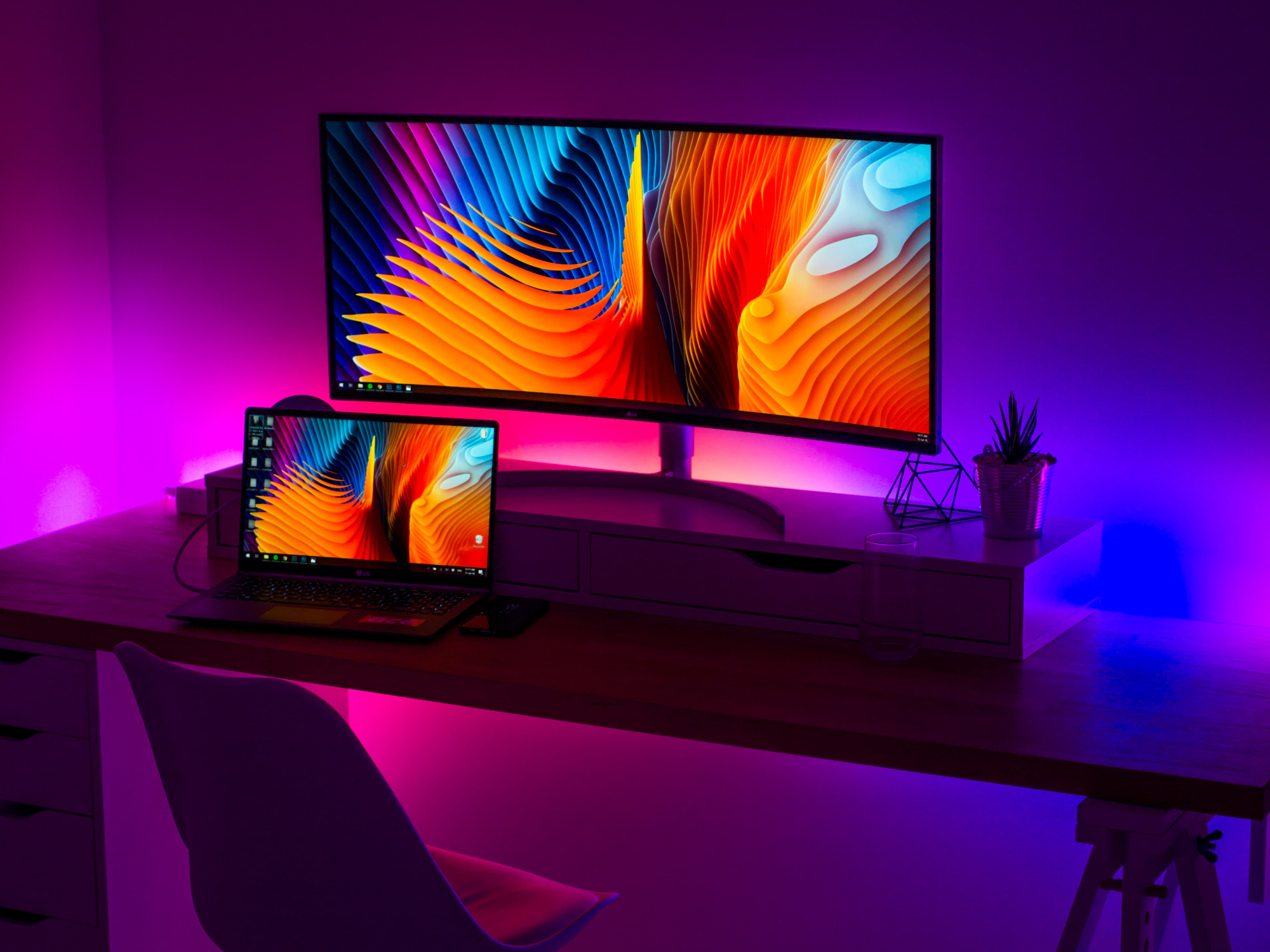 LED strip lights behind a computer desk, adding a purple glow to the room.