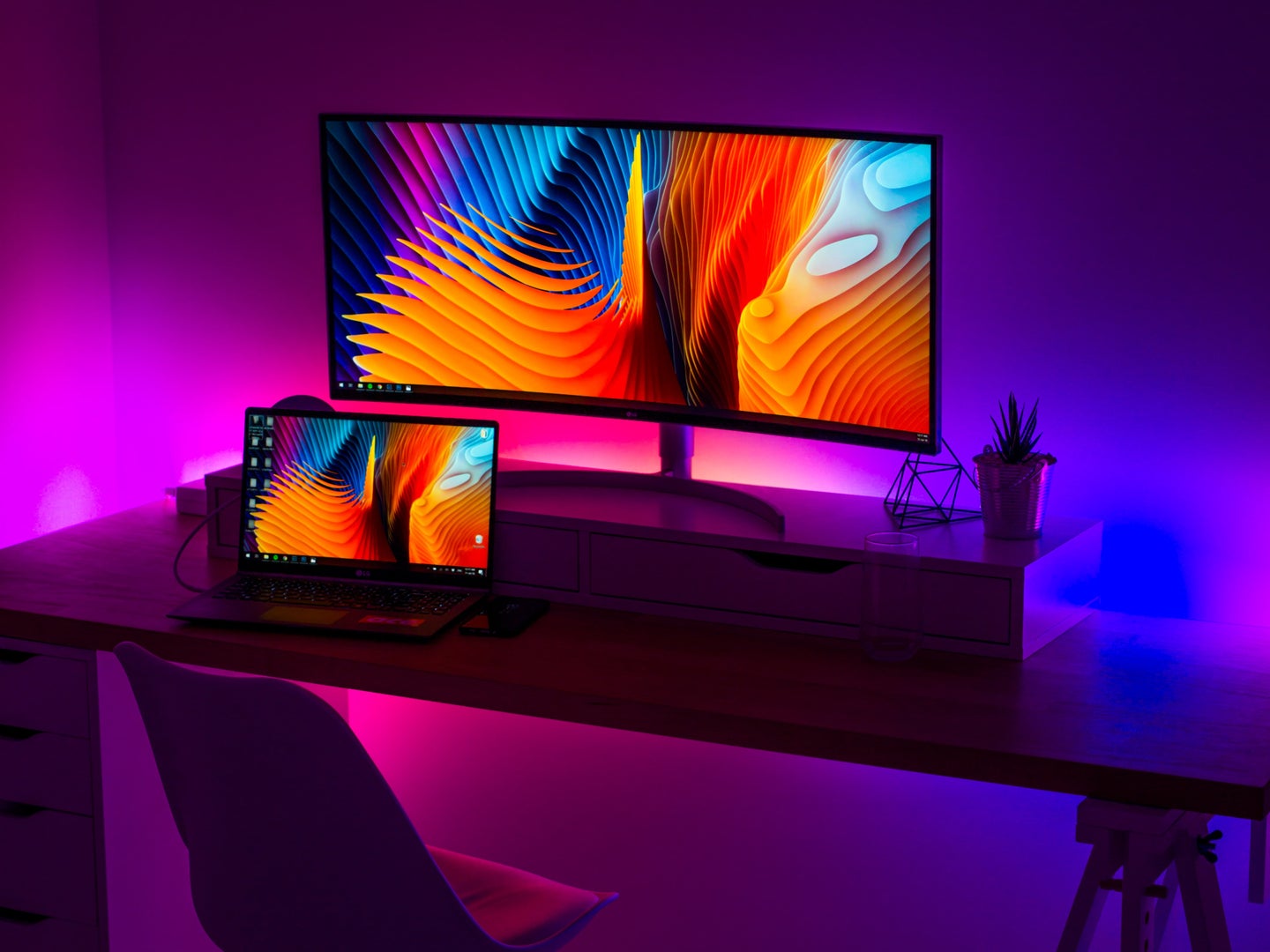 LED strip lights behind a computer desk, adding a purple glow to the room.