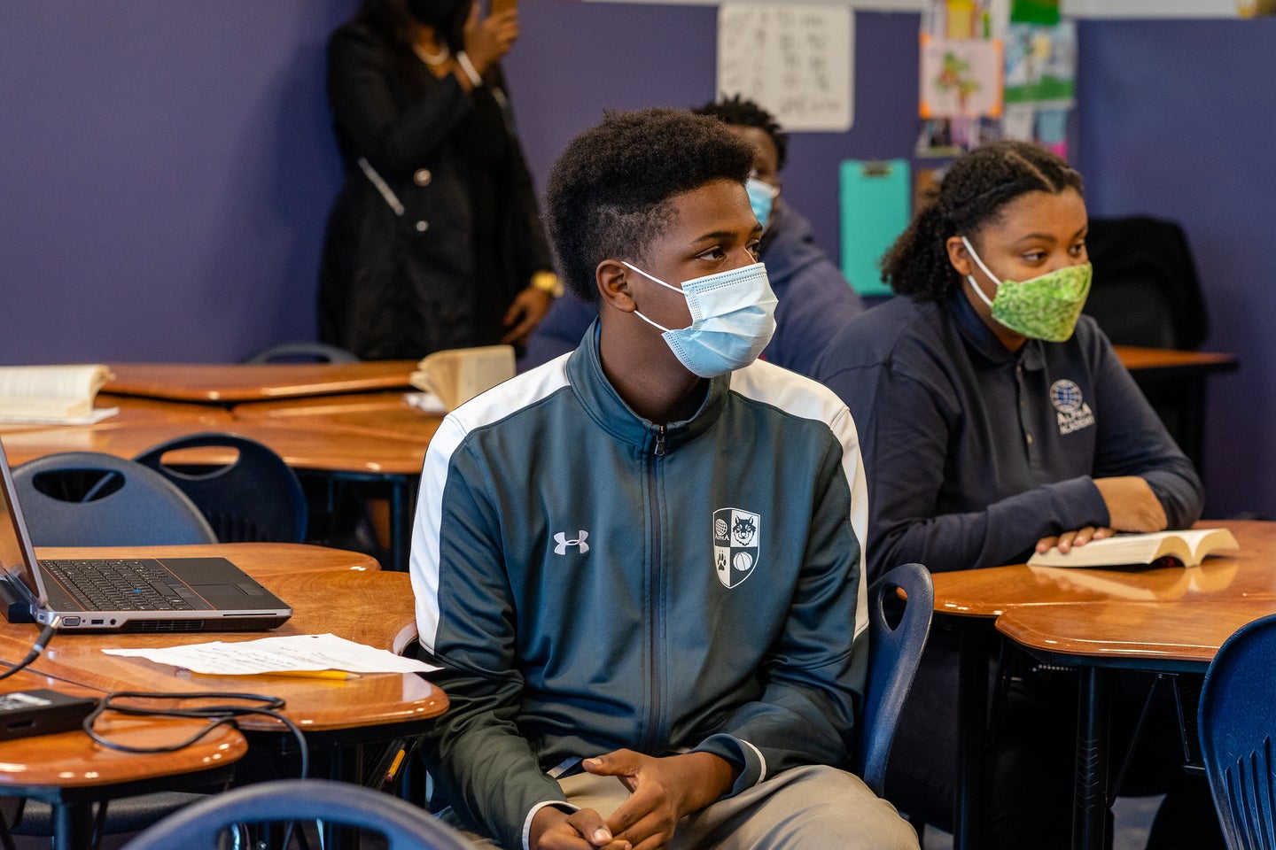 Black students in masks and track suits at desks