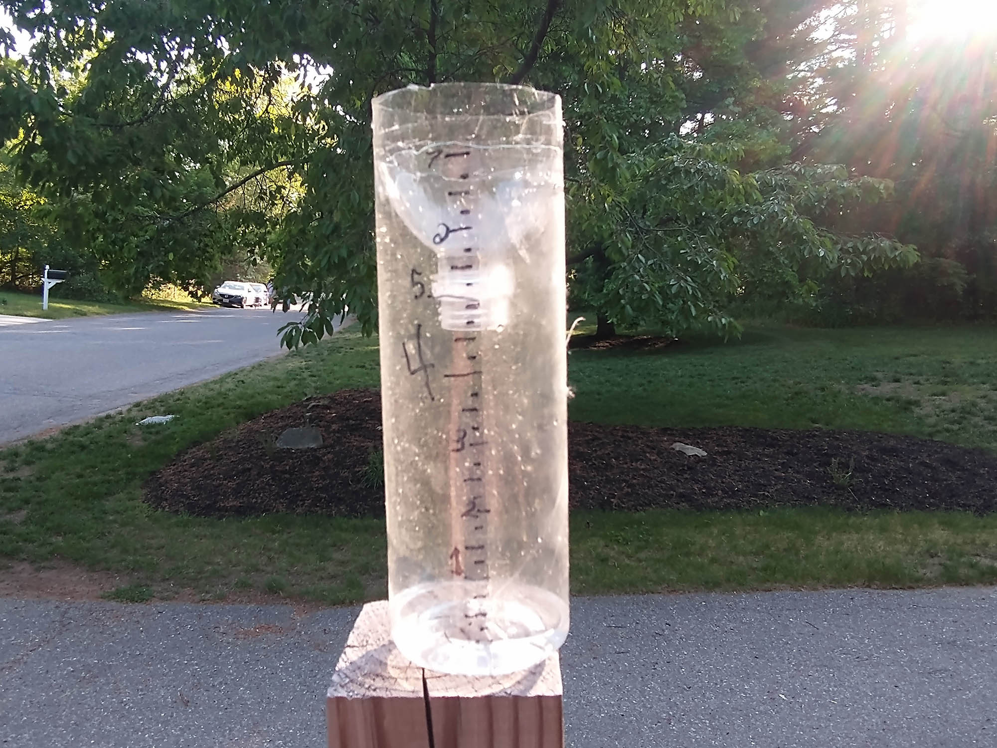 A DIY rain gauge made out of a plastic container, set up outside.