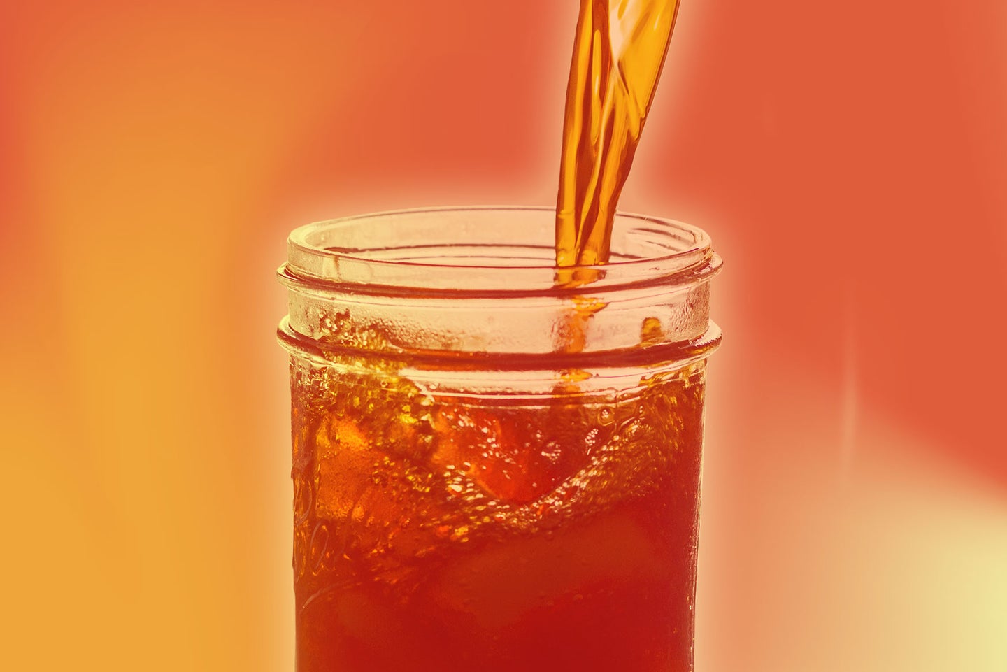 A cold drink like ice tea is poured into a glass with an orange/red overlay.