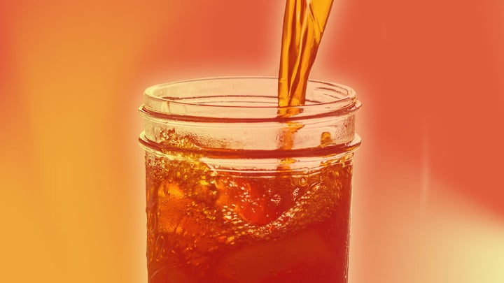A cold drink like ice tea is poured into a glass with an orange/red overlay.