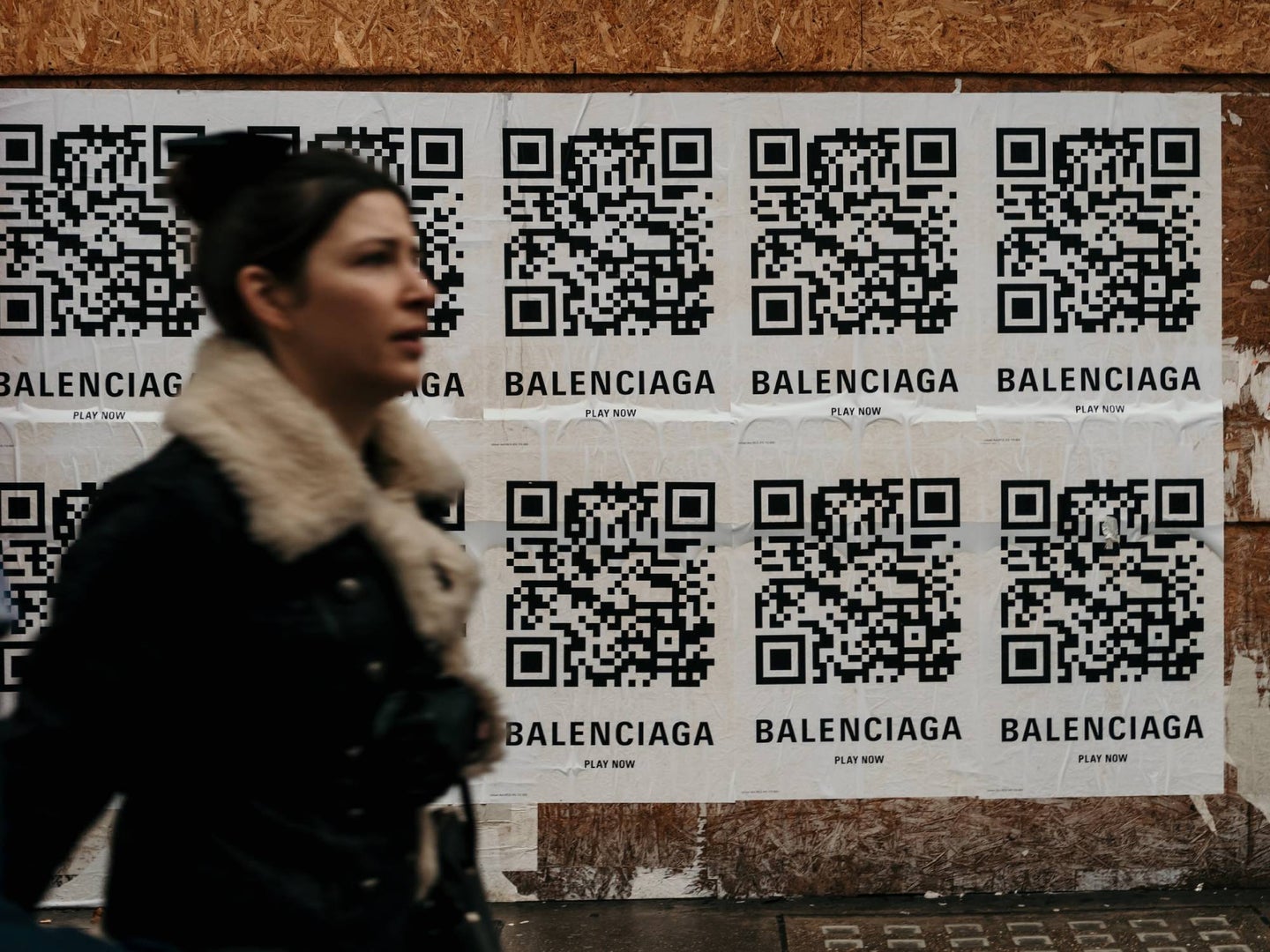Person walking in front of posters with big QR codes