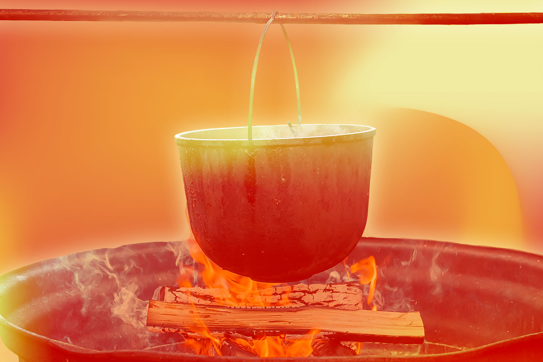 An iron pot on a spit above a cooking fire.