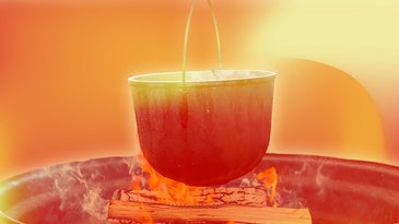 An iron pot on a spit above a cooking fire.