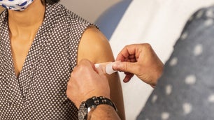 A doctor puts a bandage on a woman's arm.