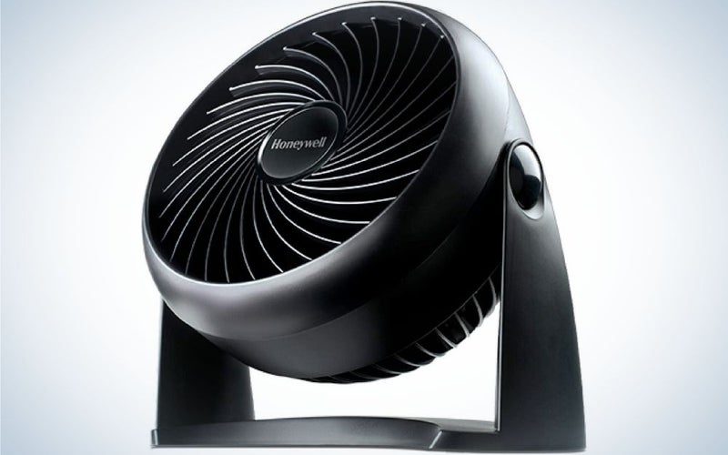A portable all black color desk fan with an upper round shape and with flat shape under it.