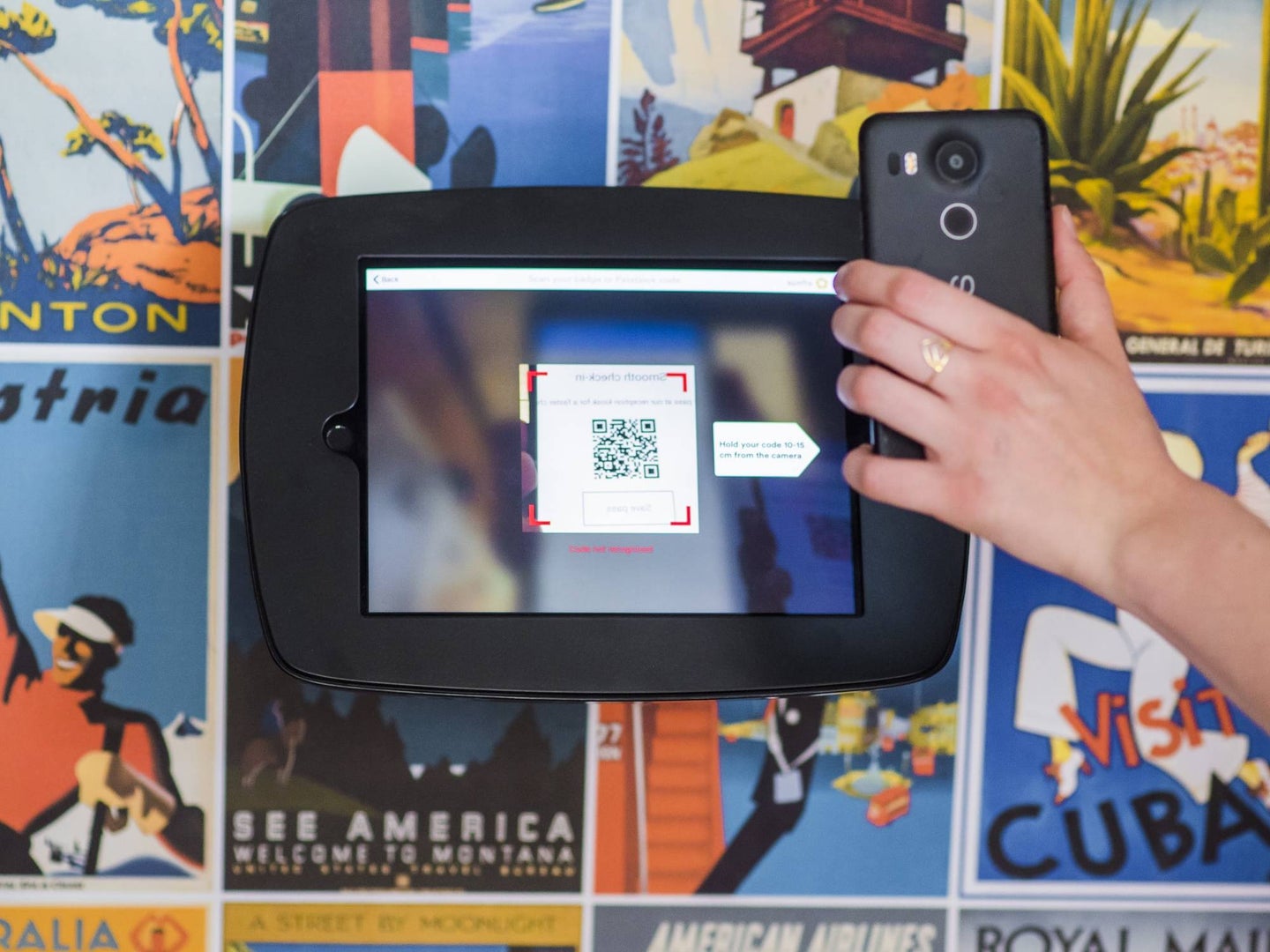 A hand holding a phone and scanning a QR code from a tablet.