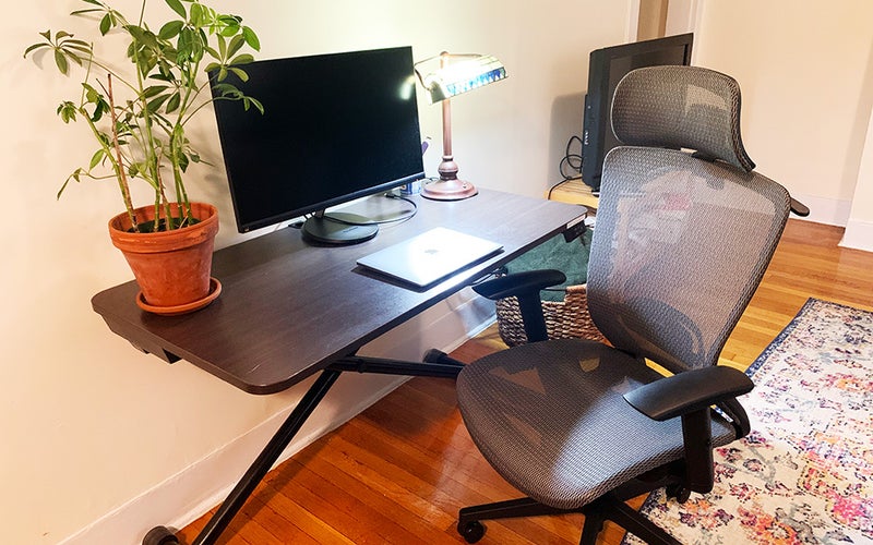 A gray mesh Flexispot OC3B Ergonomic Executive Chair in front of a standing desk with a monitor, laptop, plant, and lamp.