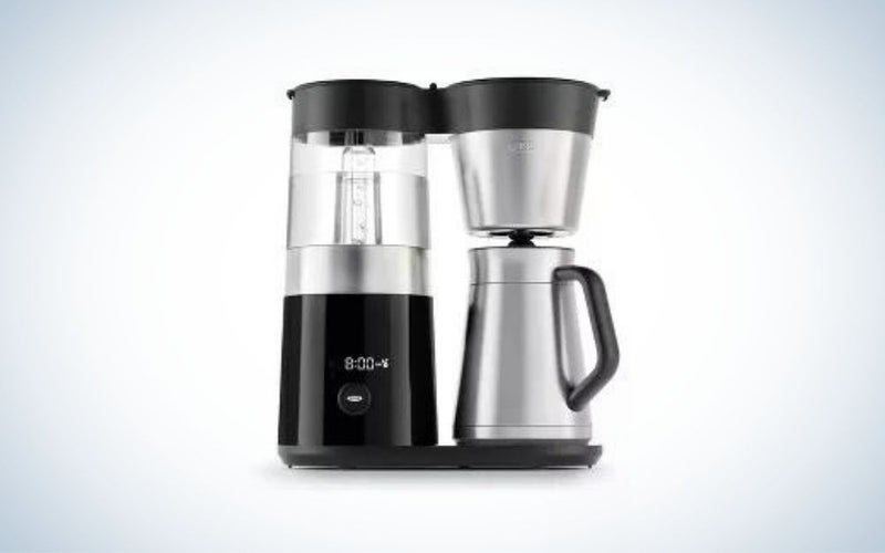 A coffee maker with two preparation utensils both black and one with a transparent plastic container on it and the other with a black lid and the whole body silver color.