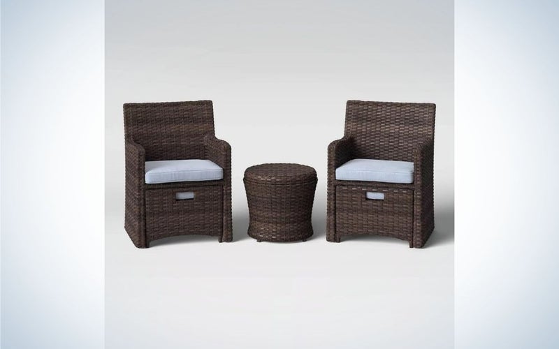 Two wooden chairs and a small table between them all in dark brown, and on the chairs there are small pillows to be more comfortable.