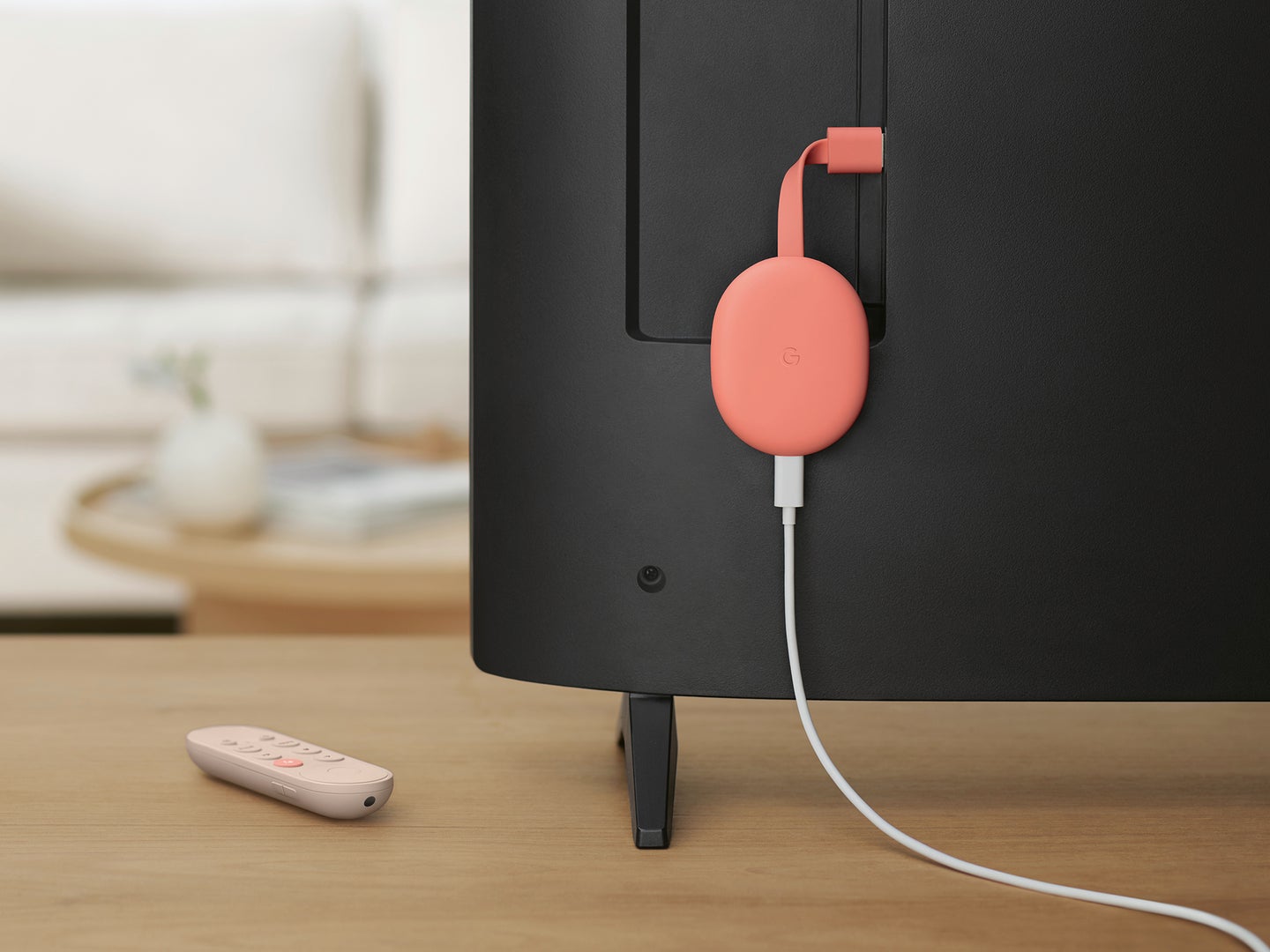 Pink Chromecast dangling from a Tv