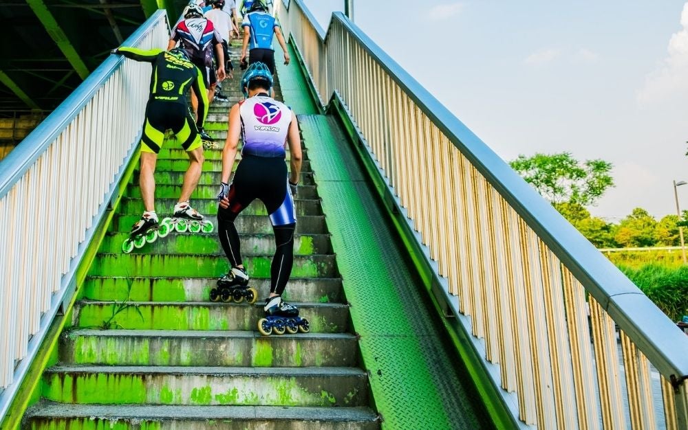 Some athletes in green sportswear as they climb the stairs wearing skates.
