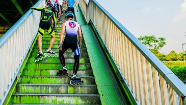 Some athletes in green sportswear as they climb the stairs wearing skates.