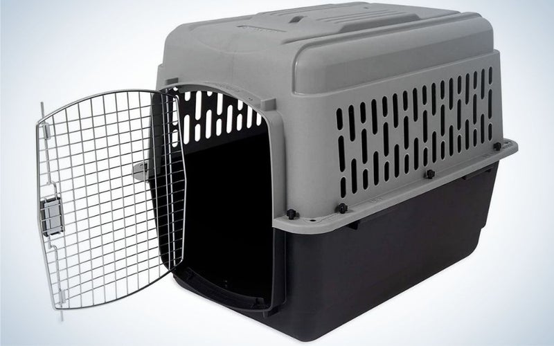 An animal cage which is made of rubber and has an open door and has black and dark gray colors.