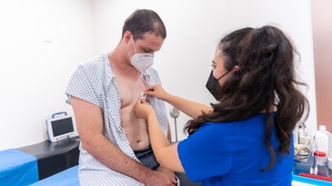 A female nurse examines a male patient's chest for heart problems.