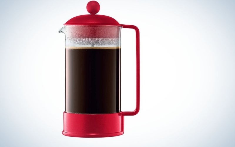 A glass kettle with a body and lid as well as a red tail and the middle part of it made of translucent glass filled with coffee in it.
