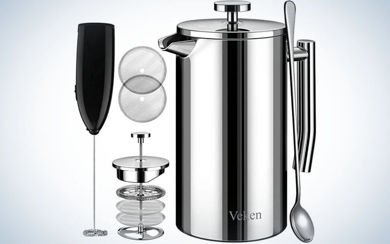 A silver kettle with a tail and lid closed from above and an apparatus with four different filters in it, as well as a black glass with a long tail and long spoons on the side of these products.
