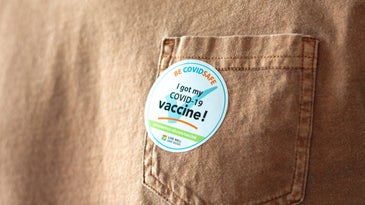 A sticker placed on the pocket of a brown tee shirt, which reads: I got my COVID-19 vaccine.
