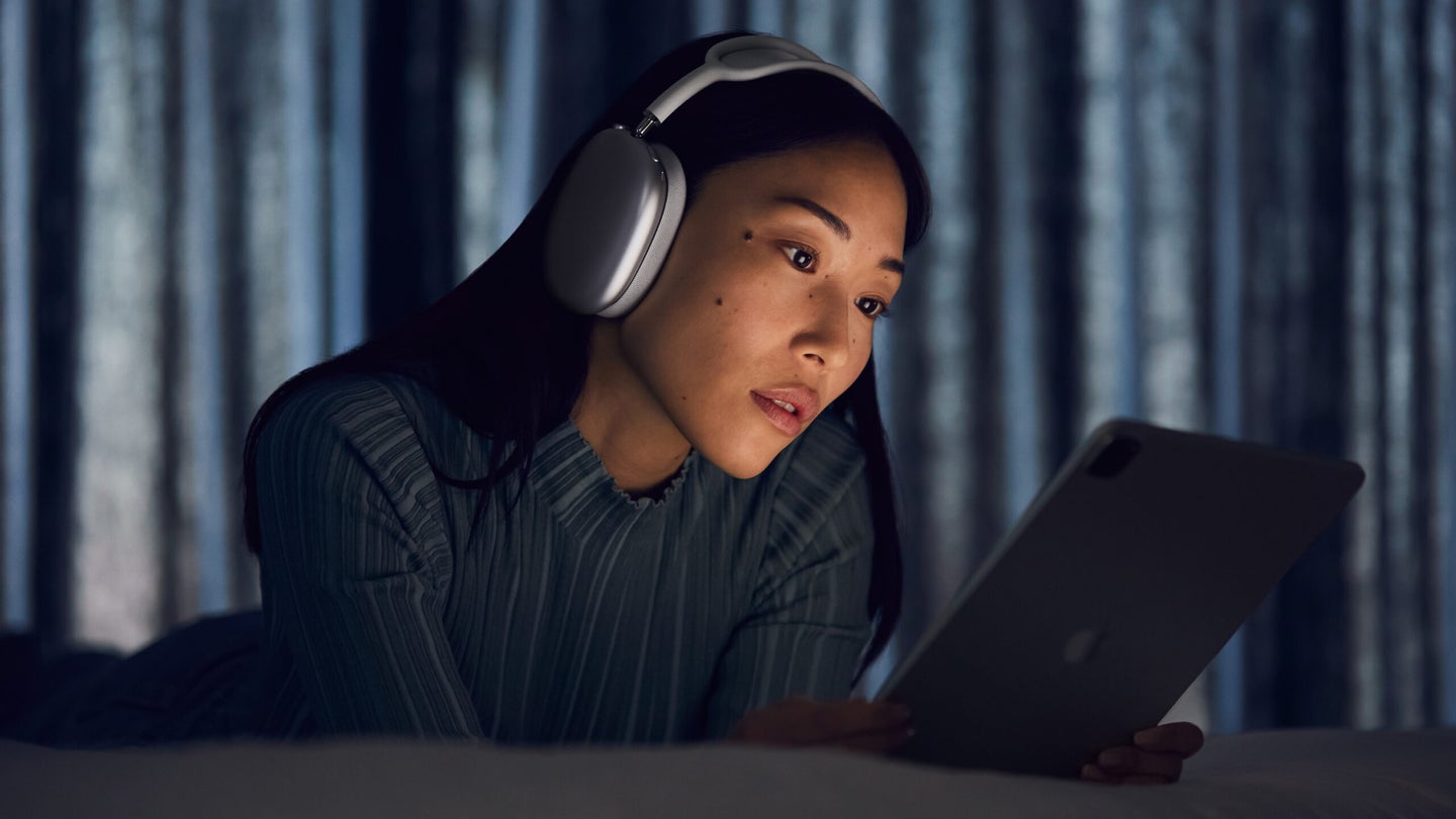 Young woman with iPad wearing Apple AirPods Max
