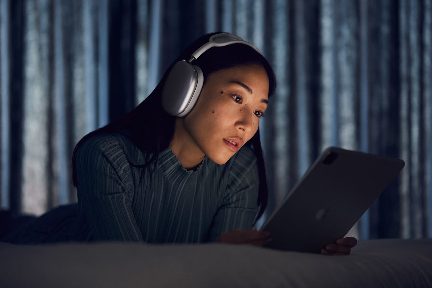 Young woman with iPad wearing Apple AirPods Max