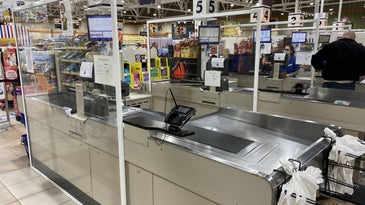 Plexiglass barriers shield cashier stations in grocery store checkout lanes.