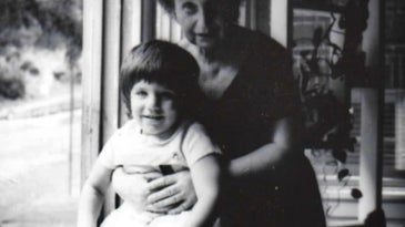Toddler with grandmother near window in black and white photo
