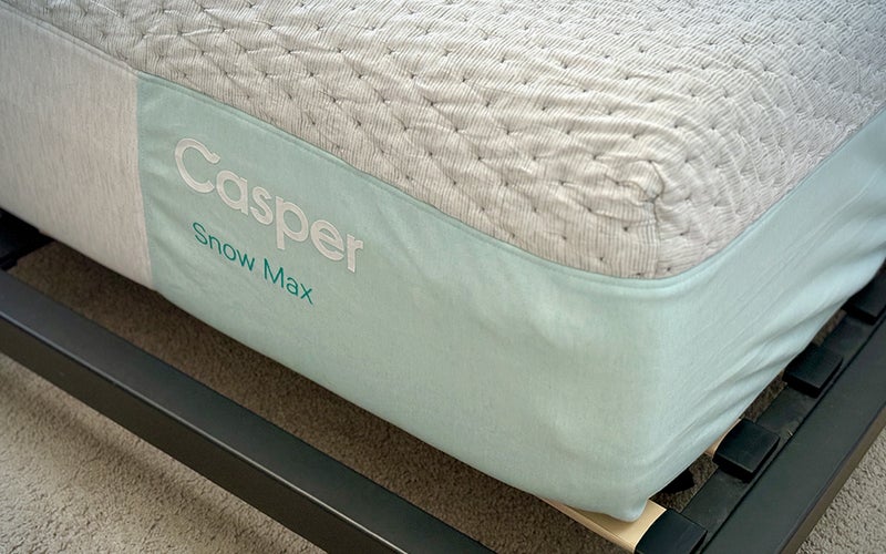 Logo corner of a Casper Snow Max best cooling mattress shown without sheets on a platform bed