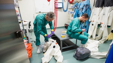 Two scientists changing out of PPE in a disease lab