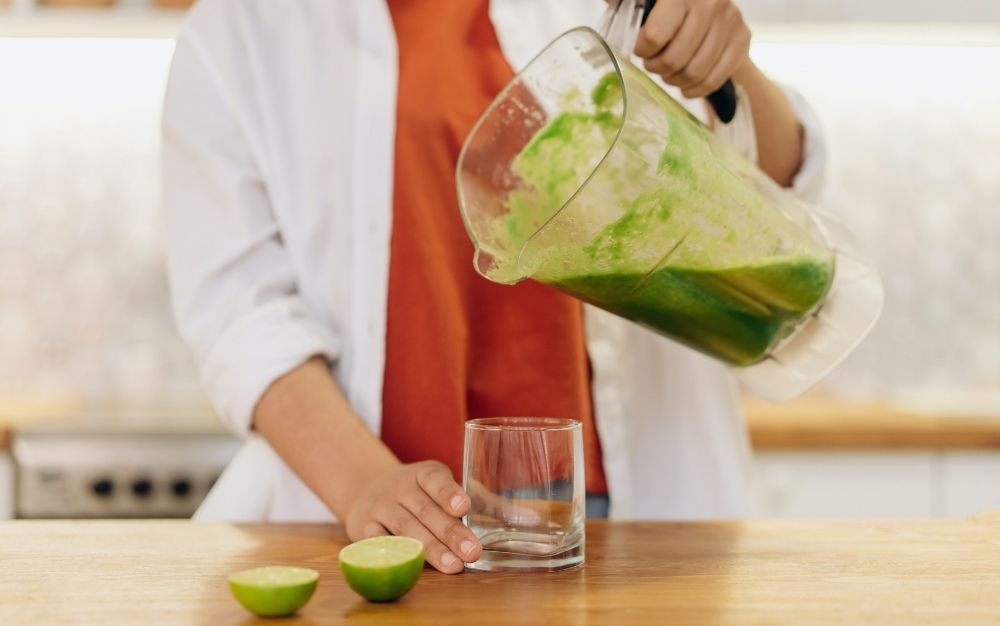 Person pouring juice from a juicer in the glass