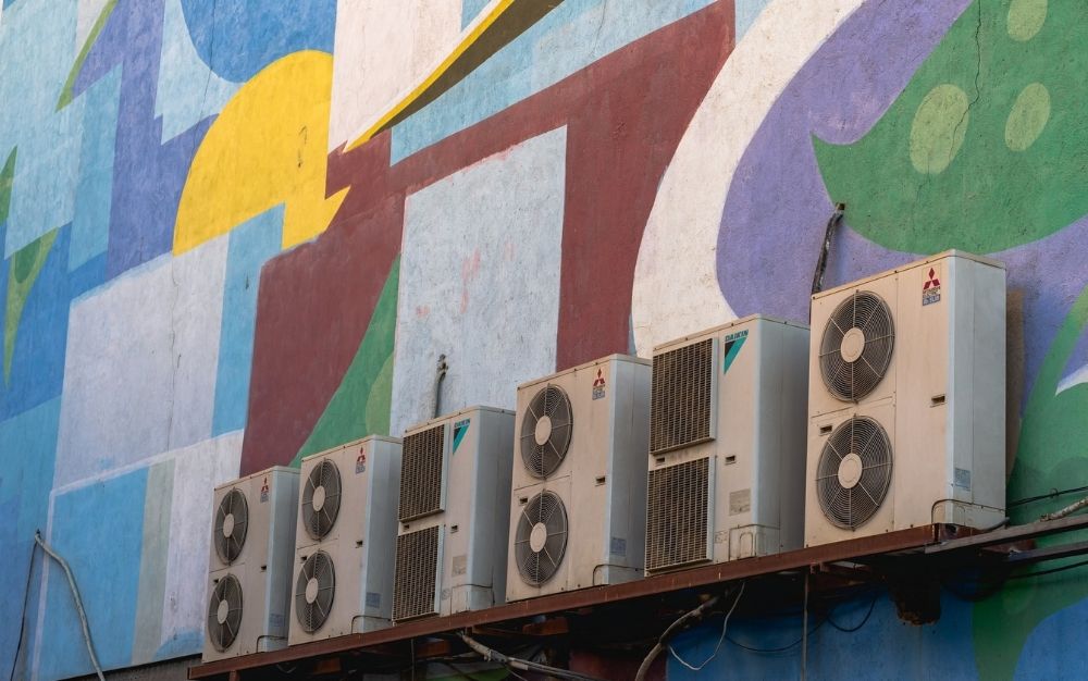 Best window air conditioner models lined up next to each other on a colored wall painted on it.