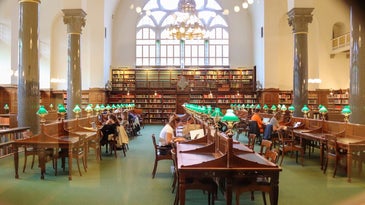 College library with students at tables and green lamps