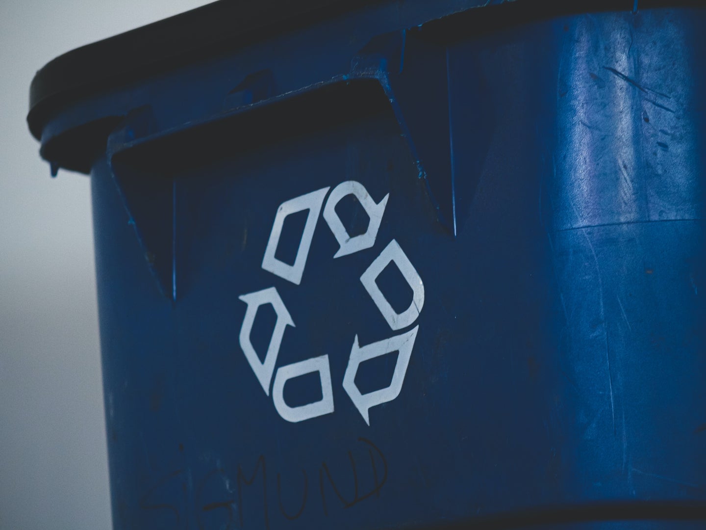 A blue recycling bin with a recycling symbol on it.