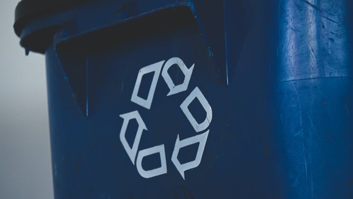 A blue recycling bin with a recycling symbol on it.