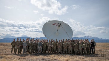 troops stand in front of a satellite dish
