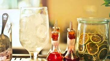 A bar cart with lined-up bottles of infused syrup.