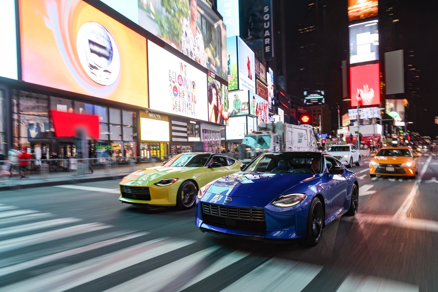 A yellow and blue 2023 Nissan Z driving in Times Square.