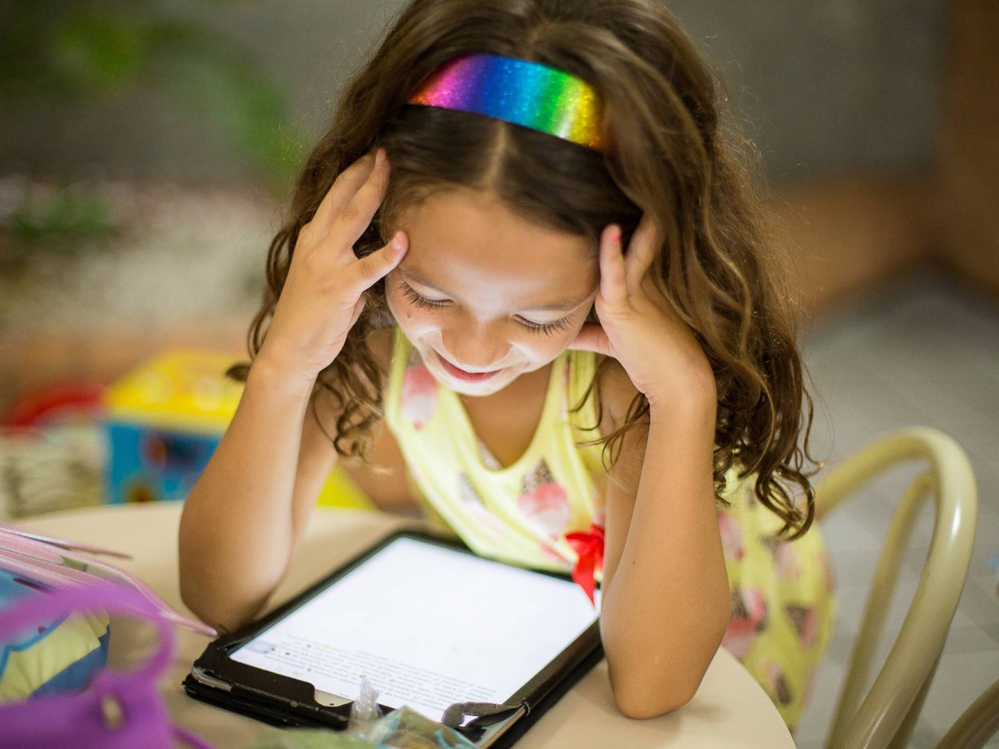 Young child sitting at a table looking at a tablet